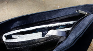 Alu-Sitzmatte mit blauweißem VILI-Wäschelabel in einer geöffneten blauen Rauhledertasche.