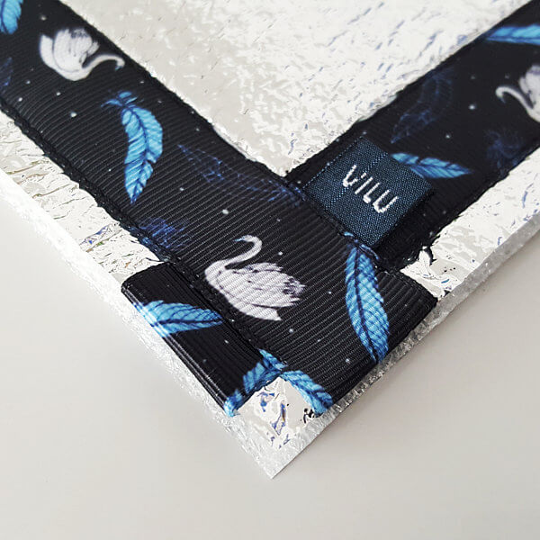 Eckgestaltung Sitzkissen mit VILU-LOGO-Wäschelabel und dunkelblaues Ripsband mit hellblauen Federn und weißen Schwänen